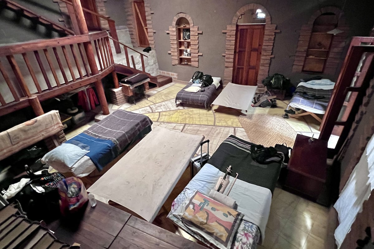 A compact room with a bed, a small table, and a staircase.