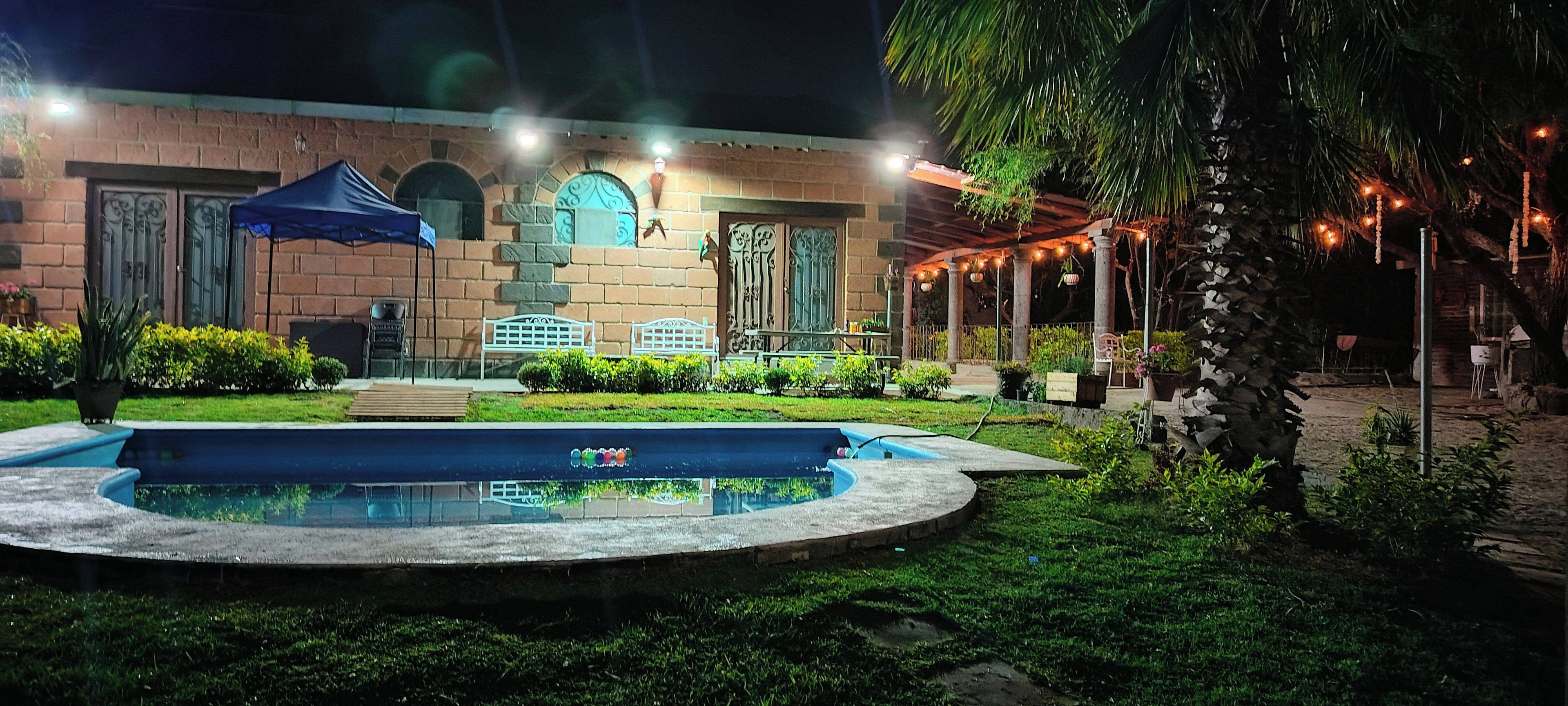 A courtyard with a pool, outdoor seating, and a covered area with string lights.