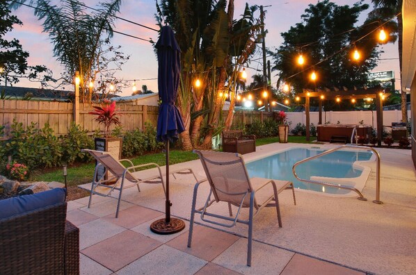 Ein Garten mit Pool, Liegestühlen und Lichterketten.