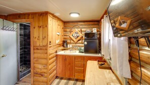 Une cuisine de taille réduite, dotée de meubles de rangement en bois, d’un réfrigérateur, d’un four à micro-ondes et d’un évier.