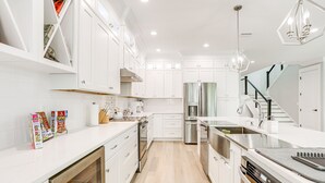 A modern kitchen with white cabinetry, stainless steel appliances, and a wooden floor. - Private Pool: Waterfront Stuart Townhome! (Stuart)