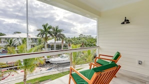 A balcony with wooden chairs and a view of a marina with boats and palm trees. - Private Pool: Waterfront Stuart Townhome! (Stuart)