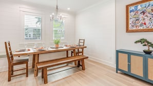A dining area with a wooden table set for four, a bench, and a blue cabinet with a bonsai tree. - Private Pool: Waterfront Stuart Townhome! (Stuart)