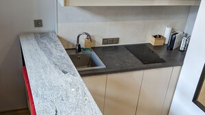 A modern kitchen with a granite countertop, stainless steel sink, and wooden cabinets.