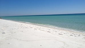 Ein Strand mit weißem Sand und klarem, blauem Wasser.