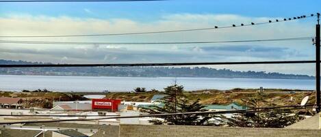 A coastal view with a clear sky, a distant shoreline, and a building with a red sign labeled "HomeGoods".