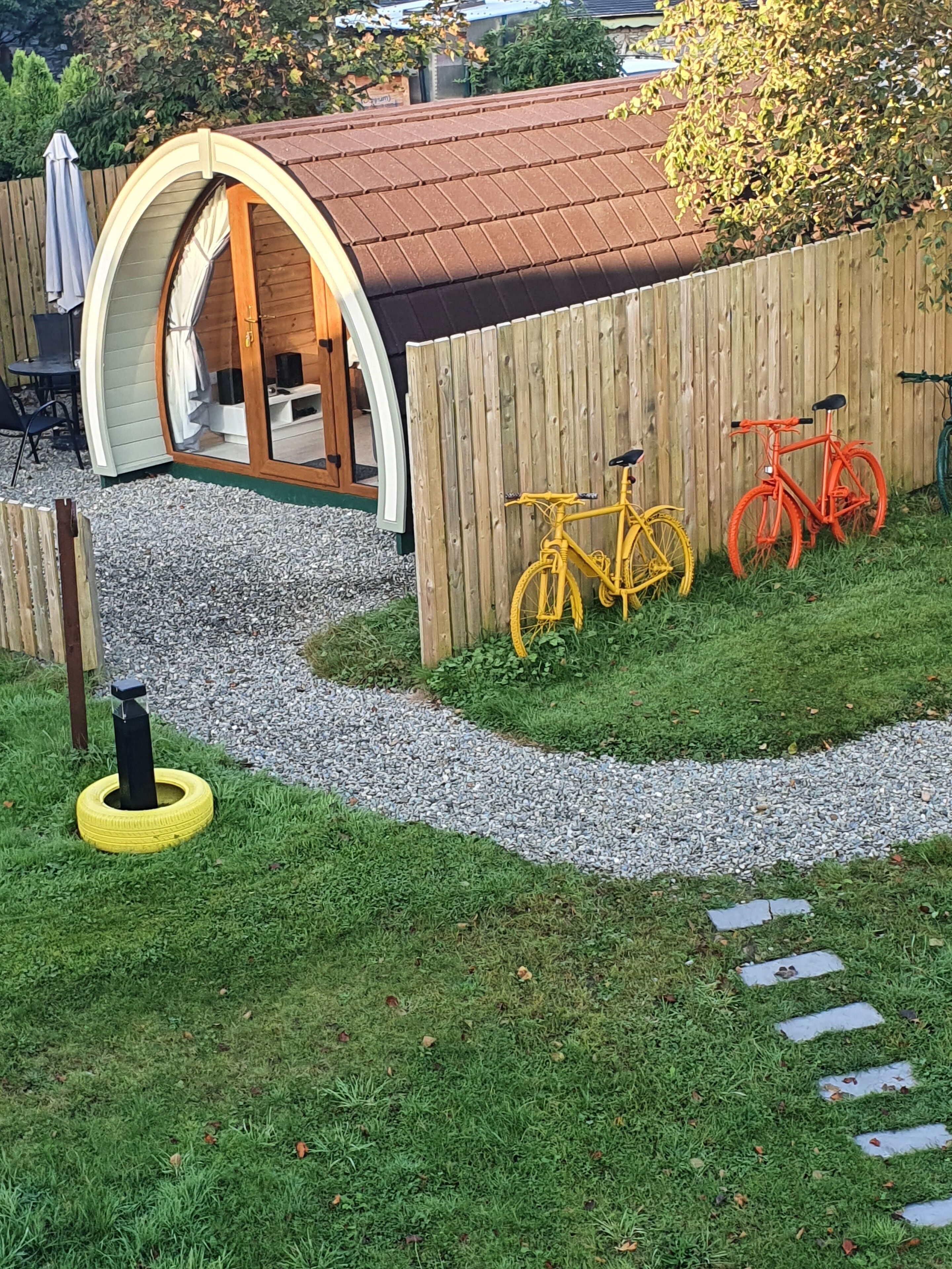 Una terraza de madera con un pequeño espacio de estar al aire libre, una valla de madera y dos bicicletas.