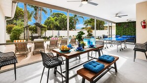 An outdoor dining area with a pool, chairs, and a table with fruit.