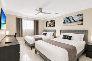 Ein Hotelzimmer mit zwei Betten, einem Schreibtisch, einem Fernseher und Bildern an den Wänden.