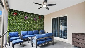 A balcony with a green wall, blue furniture, and a ceiling fan.