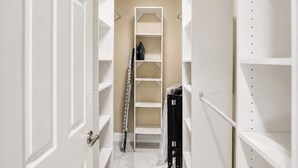 A hallway with white doors, a white shelving unit, and a ladder.