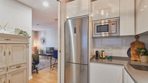A modern kitchen with stainless steel appliances, a wooden dining area, and a decorative cabinet.