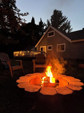 A backyard with a circular fire pit and two chairs. - Welcome to Le Chalet in Grand Marais - walking distance to Lake Superior & more! (Grand Marais)