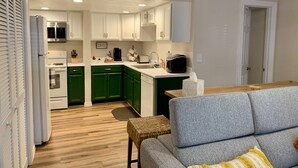 Uma cozinha compacta com armários brancos, micro-ondas, espaço para café e torradeira.