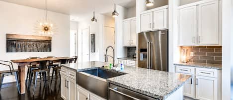 A modern kitchen with a central island, stainless steel appliances, and pendant lighting.