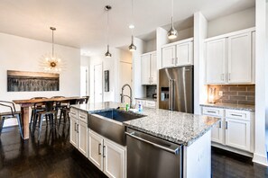 Una cocina moderna con una isla central, electrodomésticos de acero inoxidable e iluminación colgante.