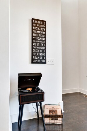A vinyl record player on a stand with a wall-mounted sign listing Nashville streets. - King-bed townhome near The Gulch | 2-Car Garage (Nashville)