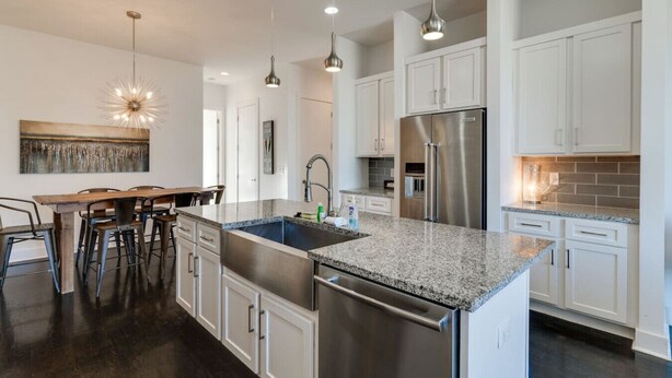 A modern kitchen with white cabinetry, stainless steel appliances, and a granite countertop. - King-bed townhome near The Gulch | 2-Car Garage (Nashville)