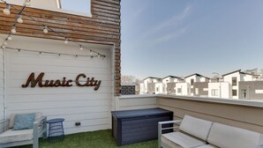 A rooftop patio with a 'Music City' sign, outdoor seating, and a view of modern buildings. - King-bed townhome near The Gulch | 2-Car Garage (Nashville)