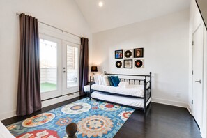 A bedroom with a bed, a patterned rug, a door, and a wall with framed pictures. - King-bed townhome near The Gulch | 2-Car Garage (Nashville)