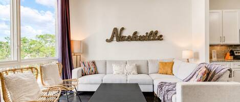 A living room with a sofa, two armchairs, a coffee table, and a wall-mounted sign.