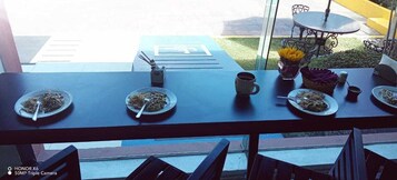 A dining table with plates of food, a coffee cup, and a vase of flowers.