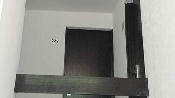 Un intérieur moderne avec une porte sombre, des murs blancs et un numéro de chambre, le 222, bien visible.
