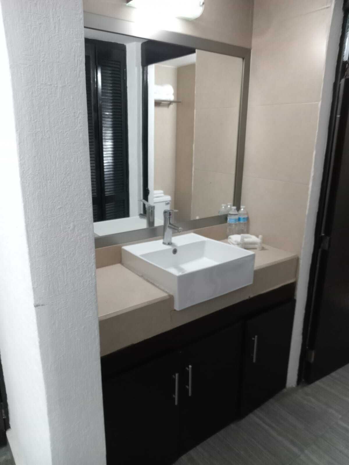 Un baño con un lavamanos blanco, un espejo y un inodoro.