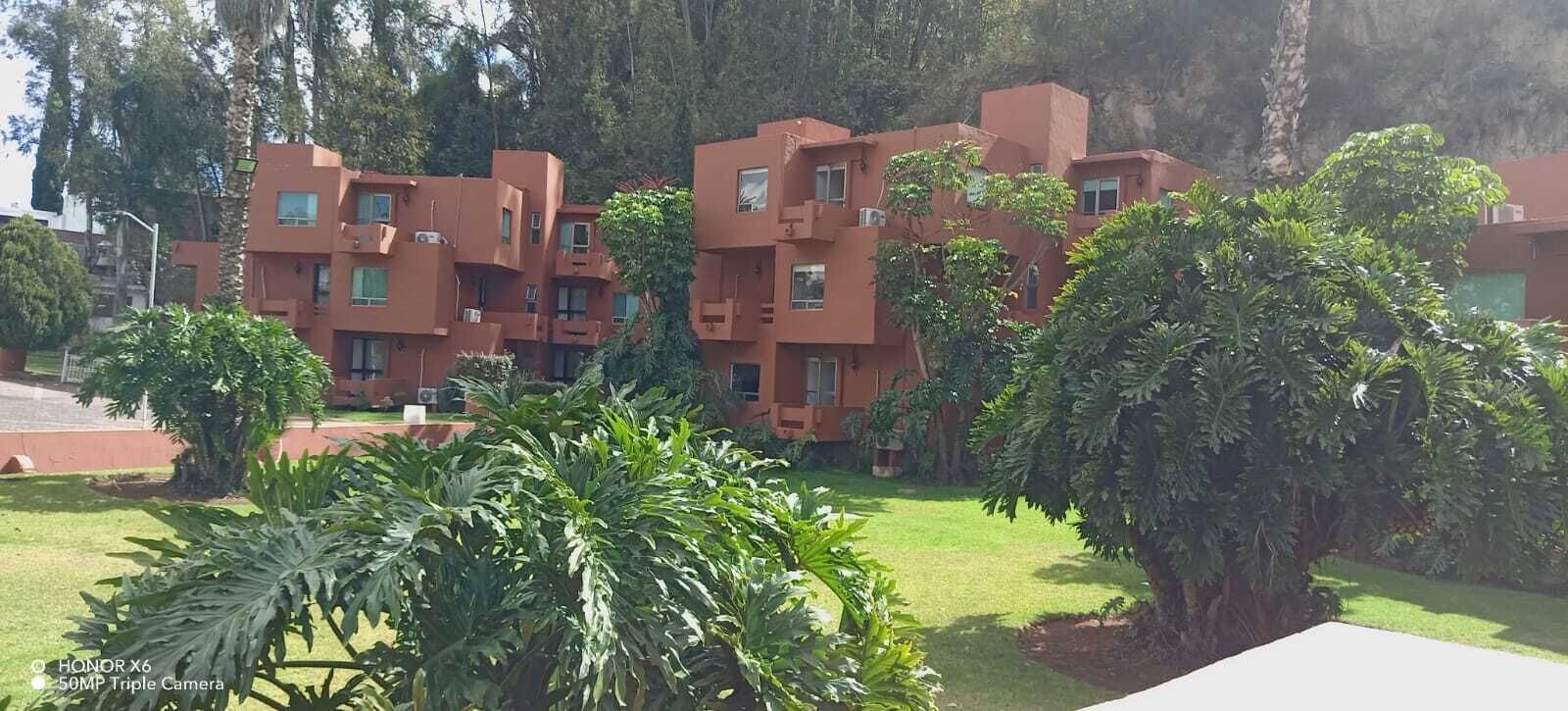 A building with multiple balconies and a well-maintained garden with various plants.