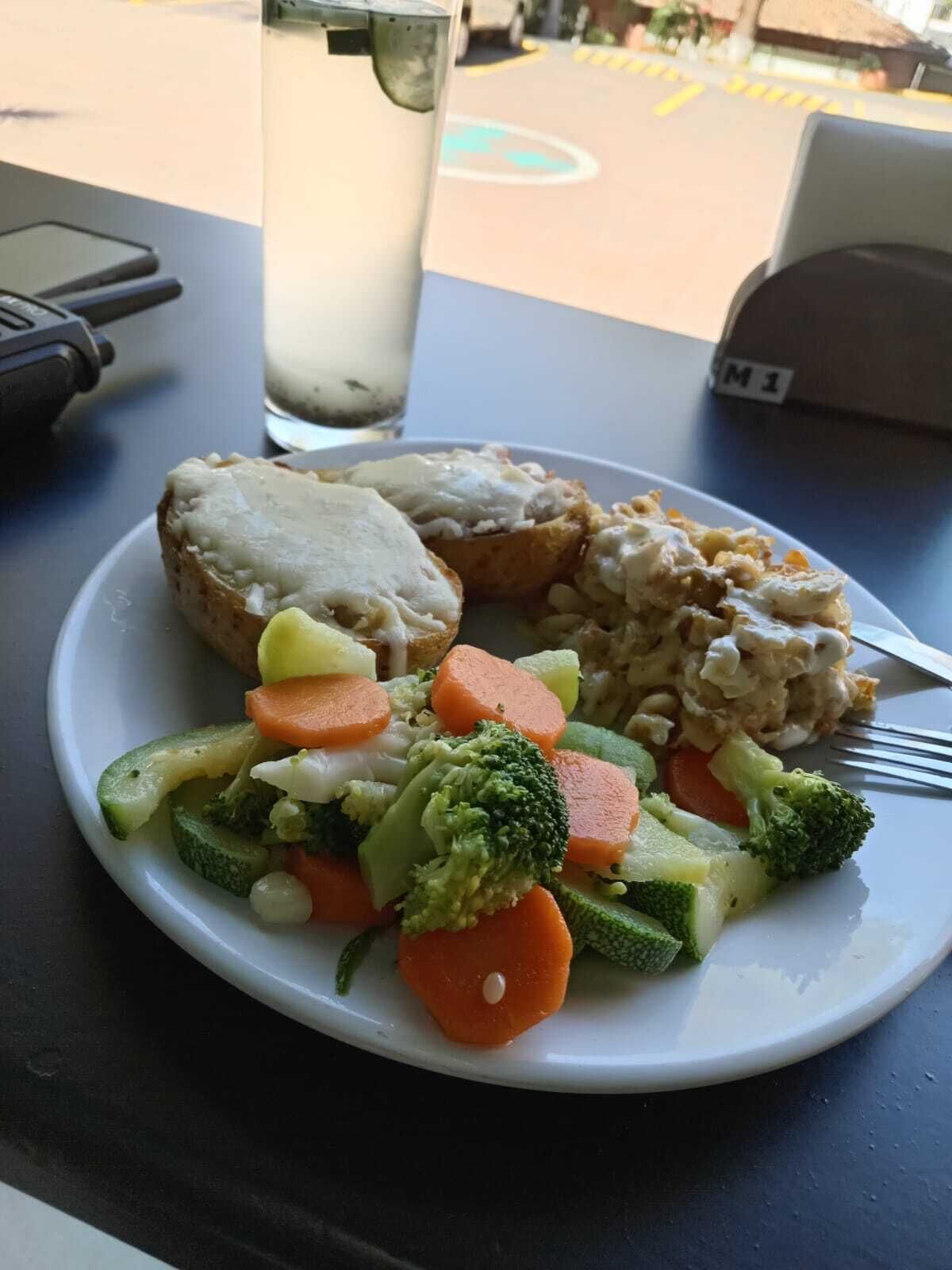 Une assiette de nourriture contenant des légumes et une boisson, posée sur une table.