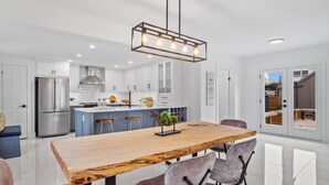 Een moderne keuken met witte kasten, een roestvrijstalen koelkast en een houten eettafel met vier stoelen.