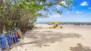 A beach with umbrellas and lounge chairs, a sandy path, and a view of the ocean. - The Anchorage - Unit 607 (Siesta Key)
