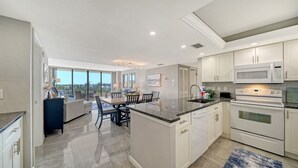 A modern kitchen with white cabinets, a granite countertop, and stainless steel appliances. - The Anchorage - Unit 607 (Siesta Key)