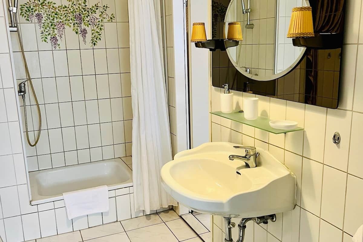 Un baño con bañera, lavabo, espejo y ducha.