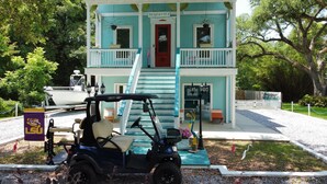 A two-story building with a teal exterior, a red door, and a balcony. - 3 Bedroom House near Old Town (Bay St. Louis)