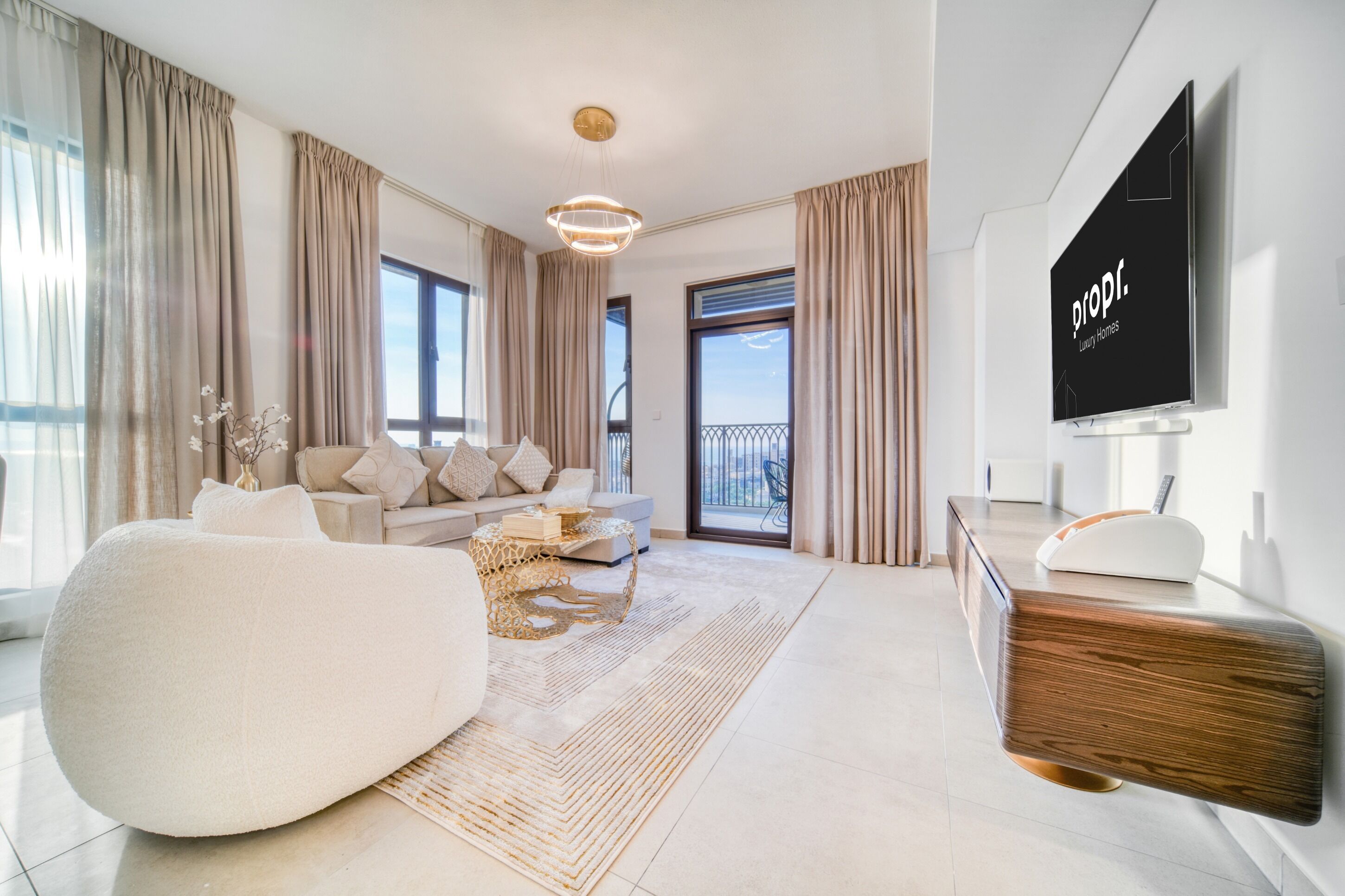 A modern living room with a sofa, coffee table, and a flat-screen TV mounted on the wall.