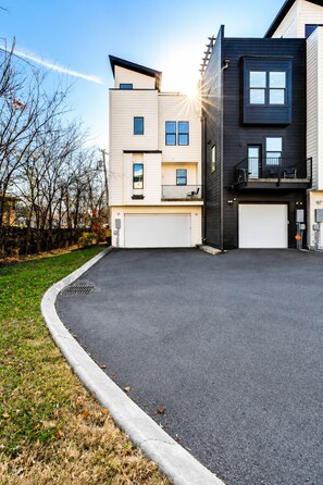 A modern two-story residential building with a garage, a small balcony, and a driveway. - 4BR townhome near The Gulch with rooftop skyline views (Nashville)