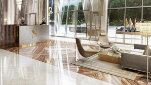 En moderne lobby med et stort glasvindue, en lysekrone og et siddeområde med en sofa og et sofabord.