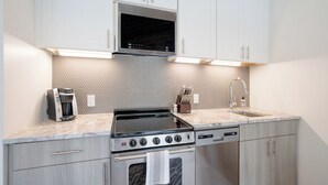 Una cucina moderna con forno a microonde, piano cottura e forno integrati, caratterizzata da un piano di lavoro in granito e una parete di fondo decorata.