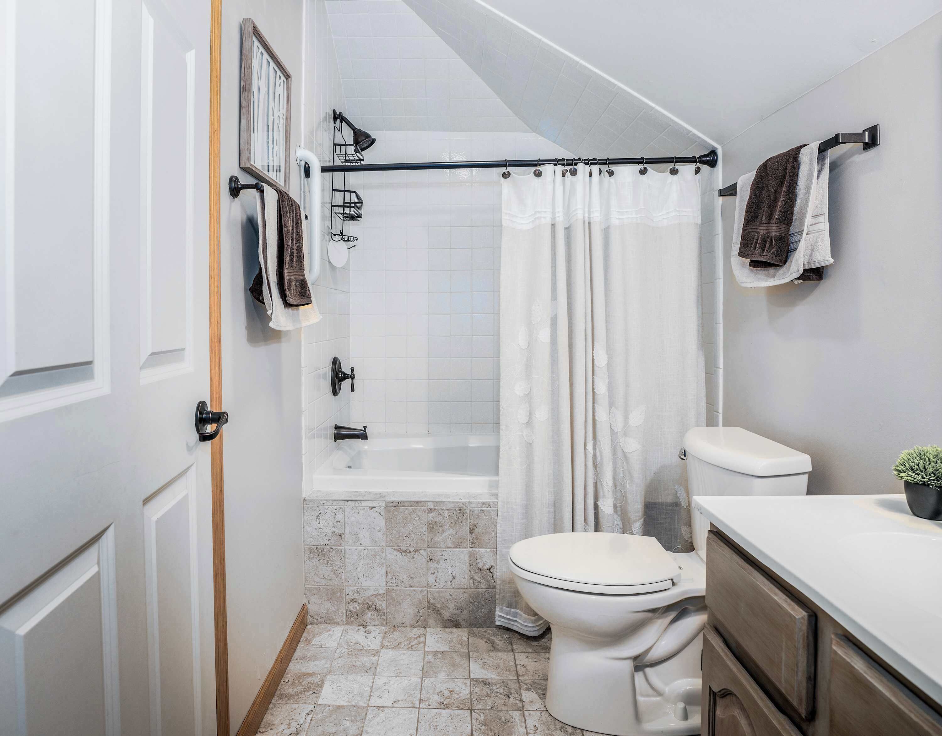 A bathroom with a shower, toilet, and a towel rack.