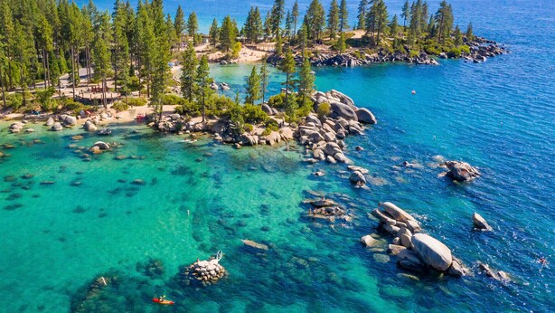 A coastal area with clear turquoise waters, rocky outcrops, and dense pine forests. - Northstar Beauty Studio Condo in Heart of Resort (Truckee)