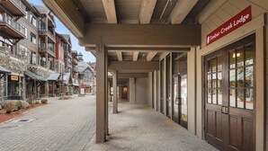 A corridor leading to Timber Creek Lodge with stone buildings on one side and a modern building on the other. - Northstar Beauty Studio Condo in Heart of Resort (Truckee)