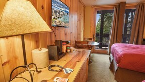 A wooden room with a bed, a desk with a lamp, a TV, and a view of the outdoors. - Northstar Beauty Studio Condo in Heart of Resort (Truckee)