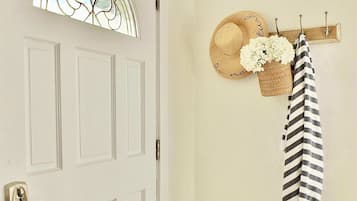 A white door with a glass panel, a hat, a basket with flowers, a striped towel, and a wooden number plaque on the floor.