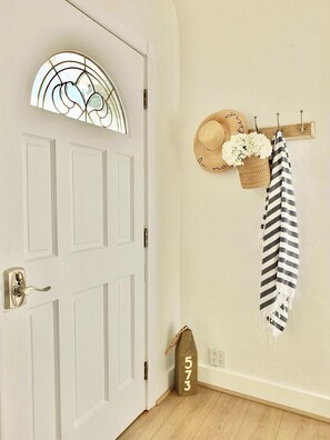 A white door with a glass panel, a hat, a basket with flowers, a striped towel, and a wooden number plaque on the floor. - Steps to Beach & Alamitos Bay - World Cup Venue Nearby (Long Beach)