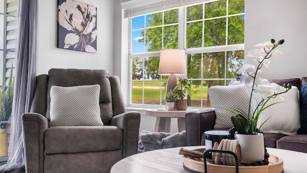 A living room with a grey sofa, a round coffee table, and a window with a view of trees. - Catch the Sunrise - Branson Mo - Holiday Hills - 2bd Condo! (Branson)