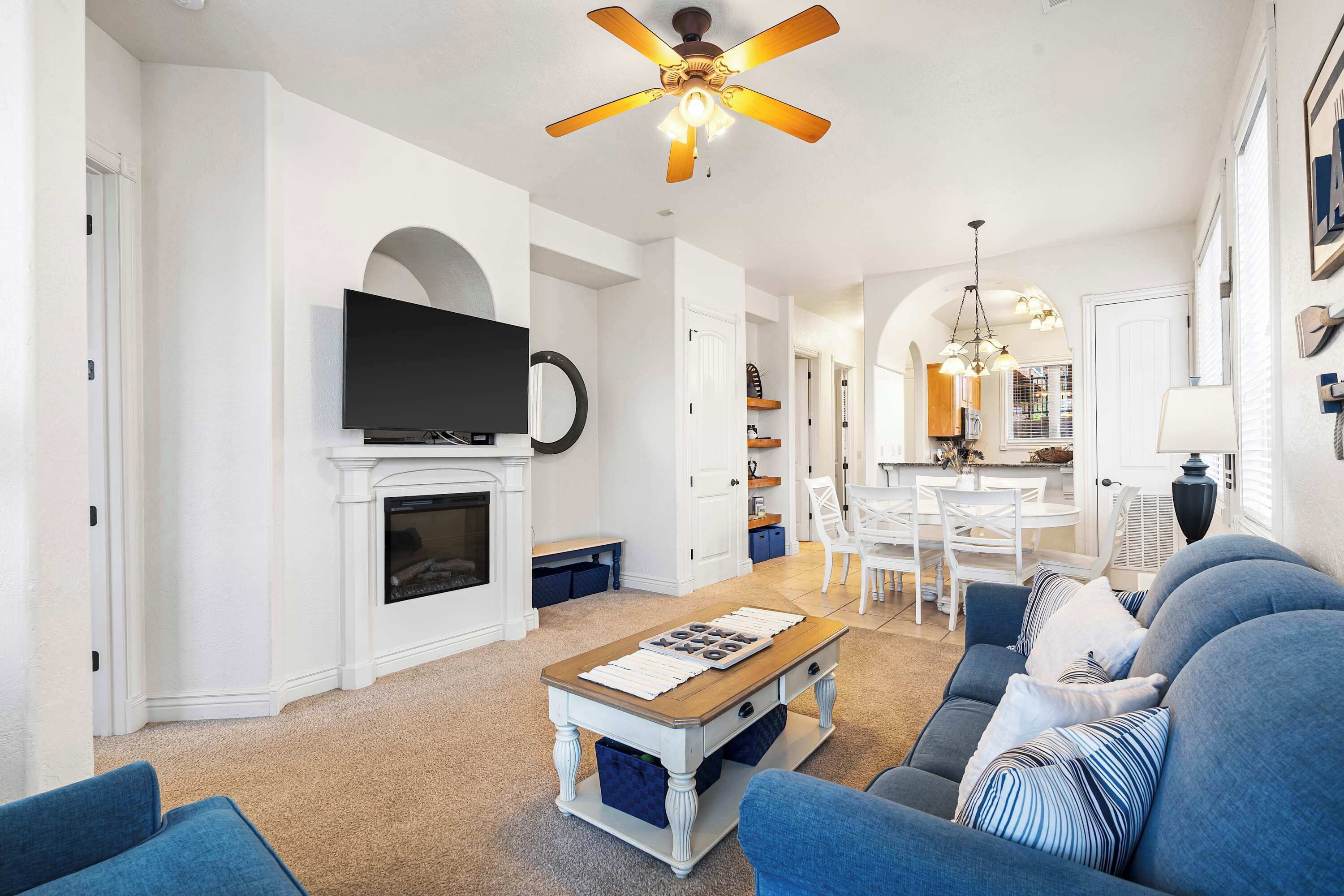 A living room with a fireplace, a television, and a ceiling fan.