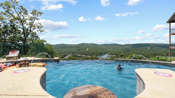A swimming pool with a view of mountains, a lounge area with chairs, and a hot tub. - Cliffside Lake Retreat - 2 Bdr, Walk to Table Rock (Branson)