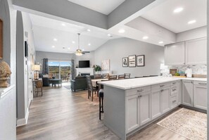 A modern kitchen with grey cabinets, a large island, and a dining area with a view. - Great Escape Duo (Branson)