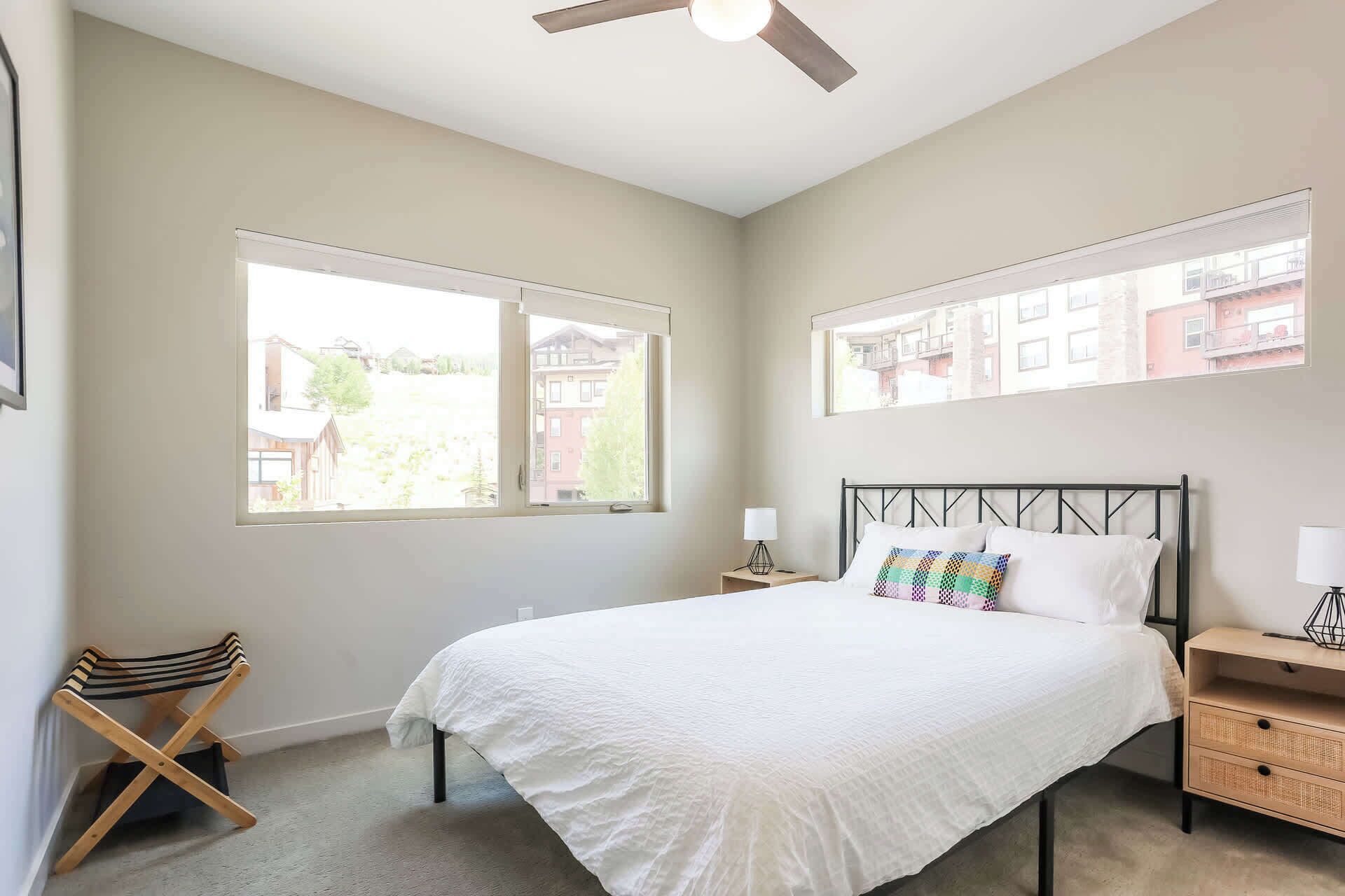 A bedroom with a bed, a nightstand, a chair, and a ceiling fan.